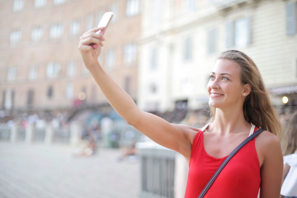 Comment se prendre en photo — personne prenant un selfie en extérieur avec smartphone